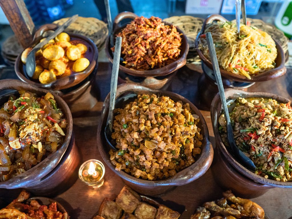 indonesian cuisine buffet with multiple wooden dishes of different food