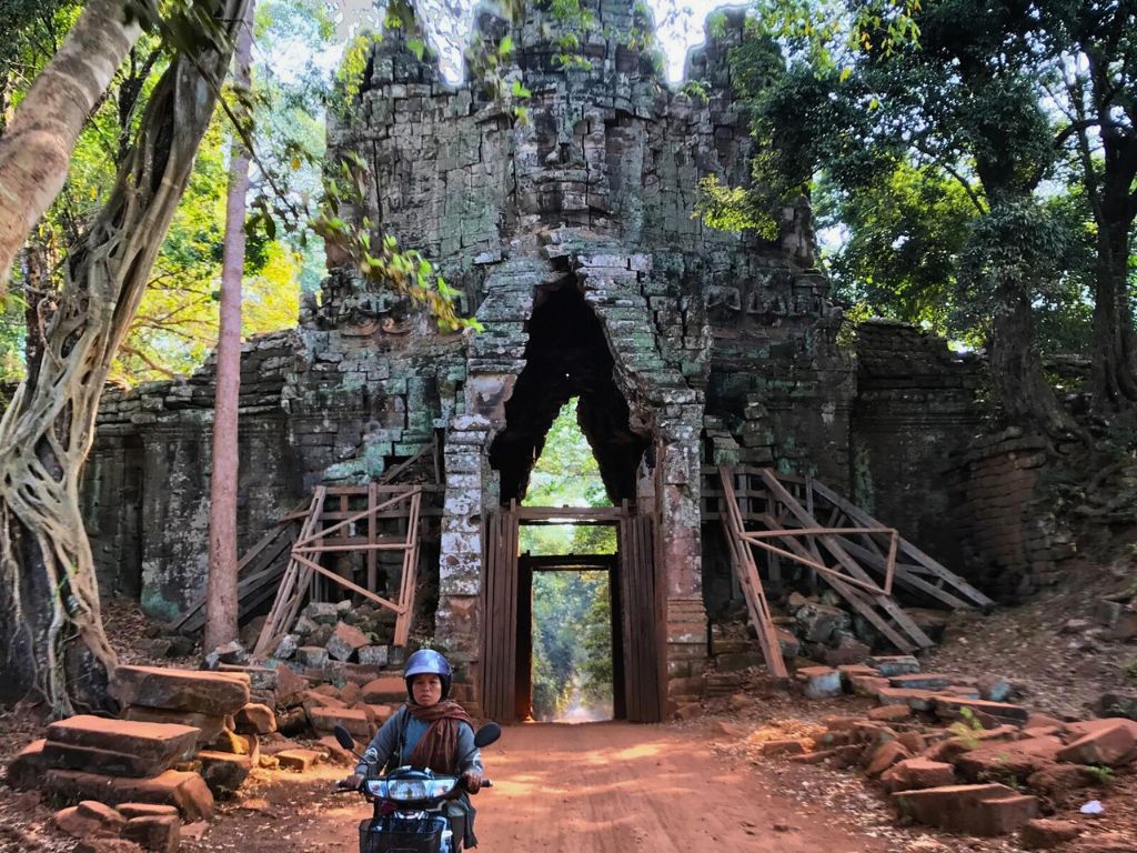 angkor wat temple with woman riding scooter in foreground