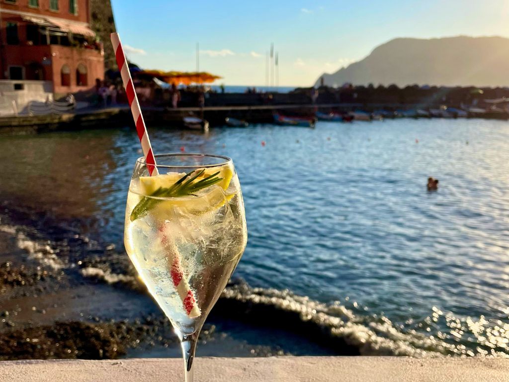aperitivo glass with harbor at sunset behind