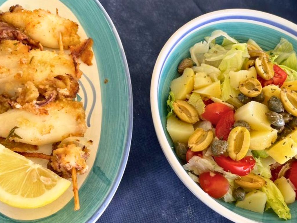 two dishes with stuffed and breaded calamari pieces, and a salad with olives, capers and tomatoes