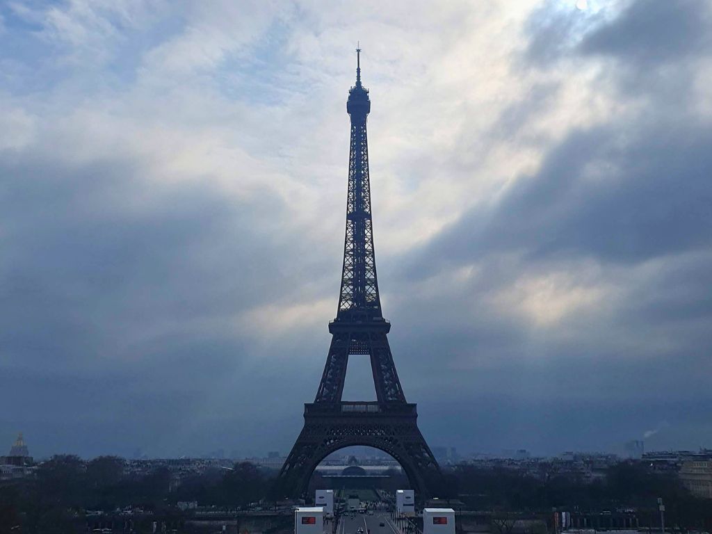 view of eiffel tower from trocadero terrace with moody grey sky behind in paris in december