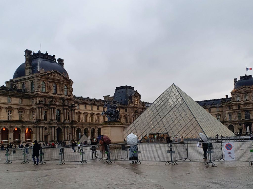 louvre courtyard with pyramid on a rainy day in paris in december